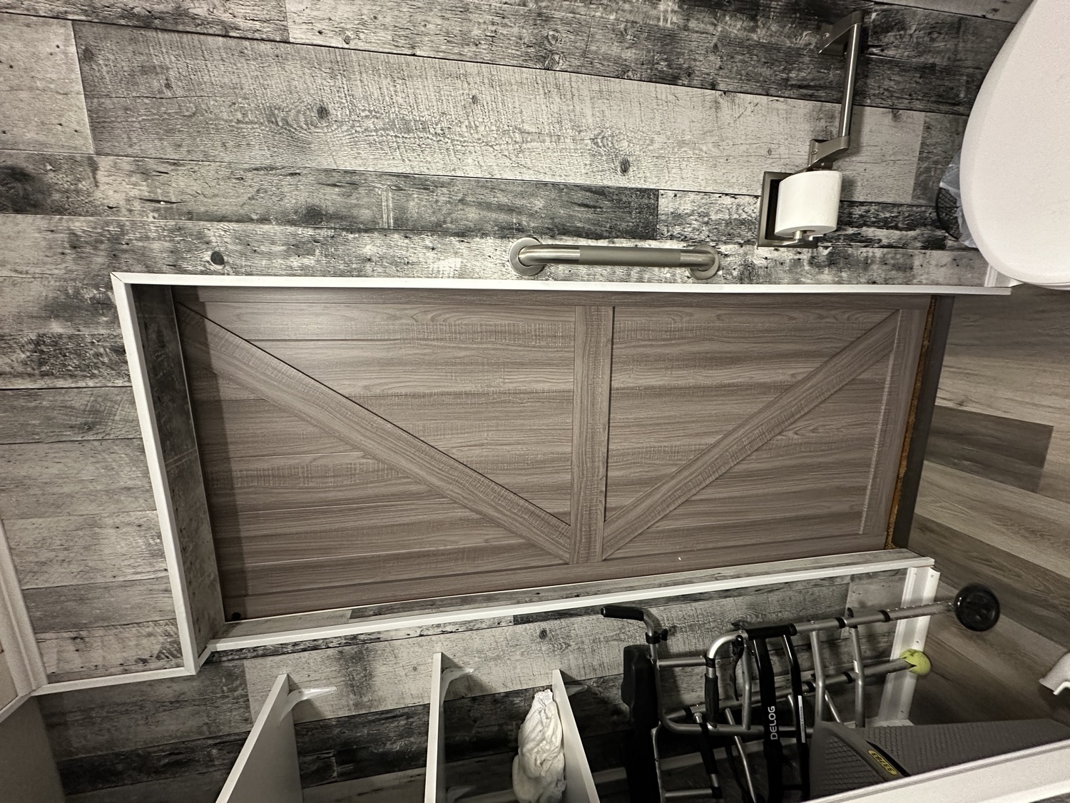 Remodeled accessible bathroom with rustic plank walls, barn door, and grab bars