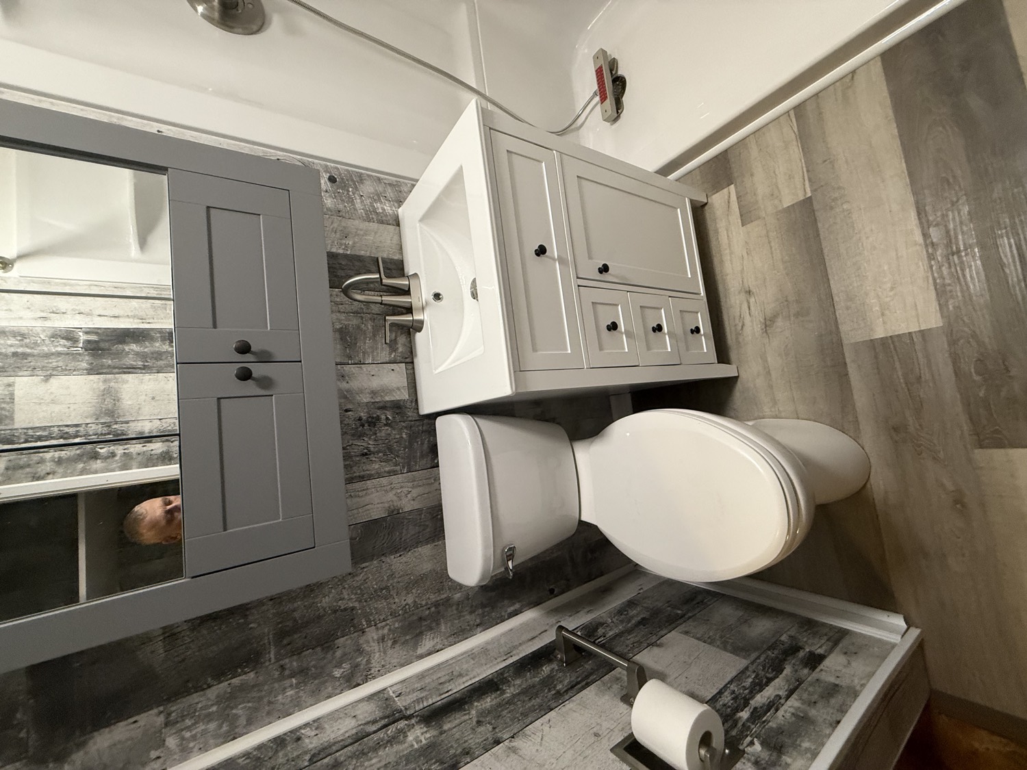 Updated bathroom with new white vanity, rustic accent wall, and walk-in shower
