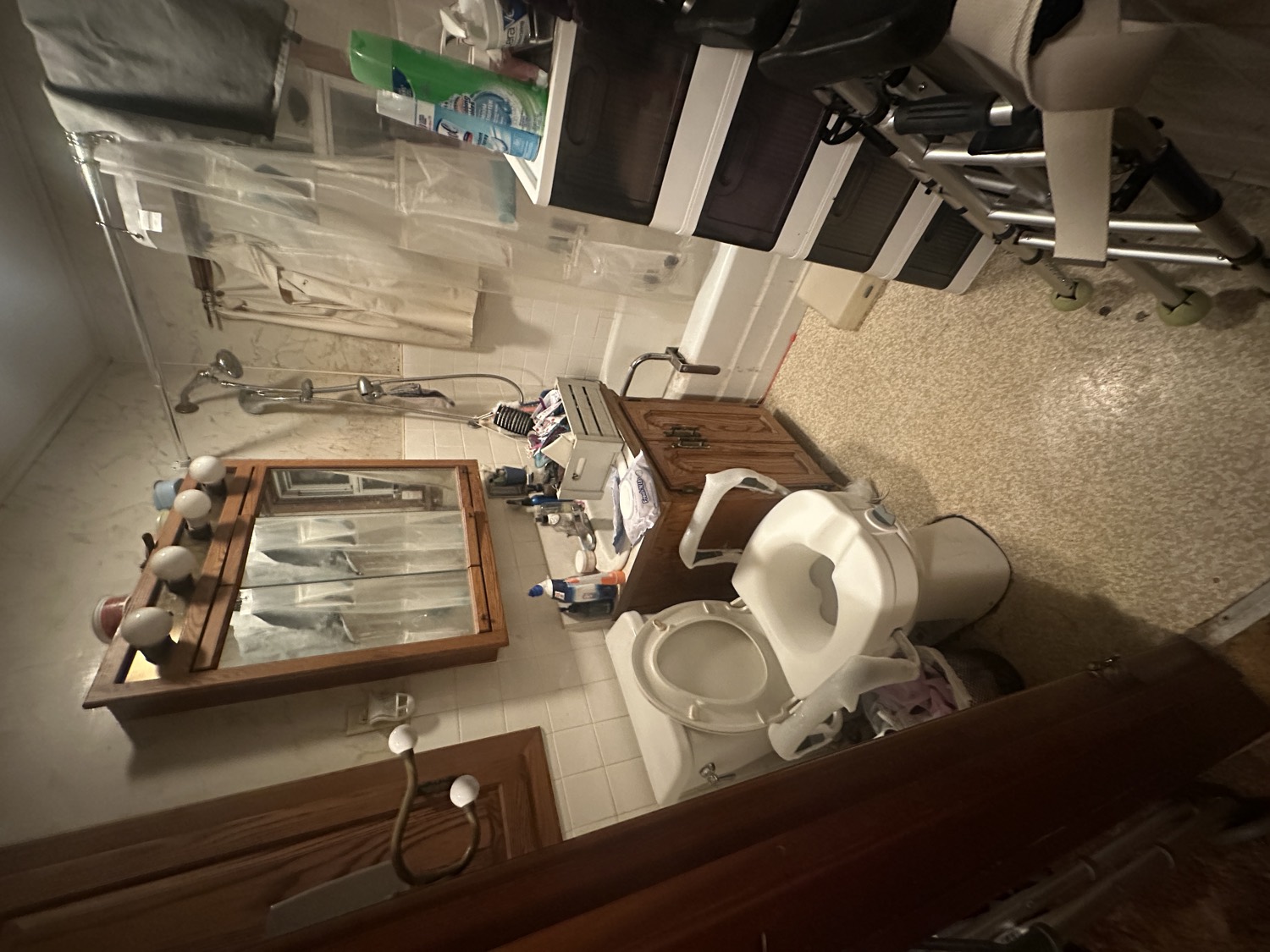 Dated, cramped bathroom before remodeling, with old fixtures and a mobility walker