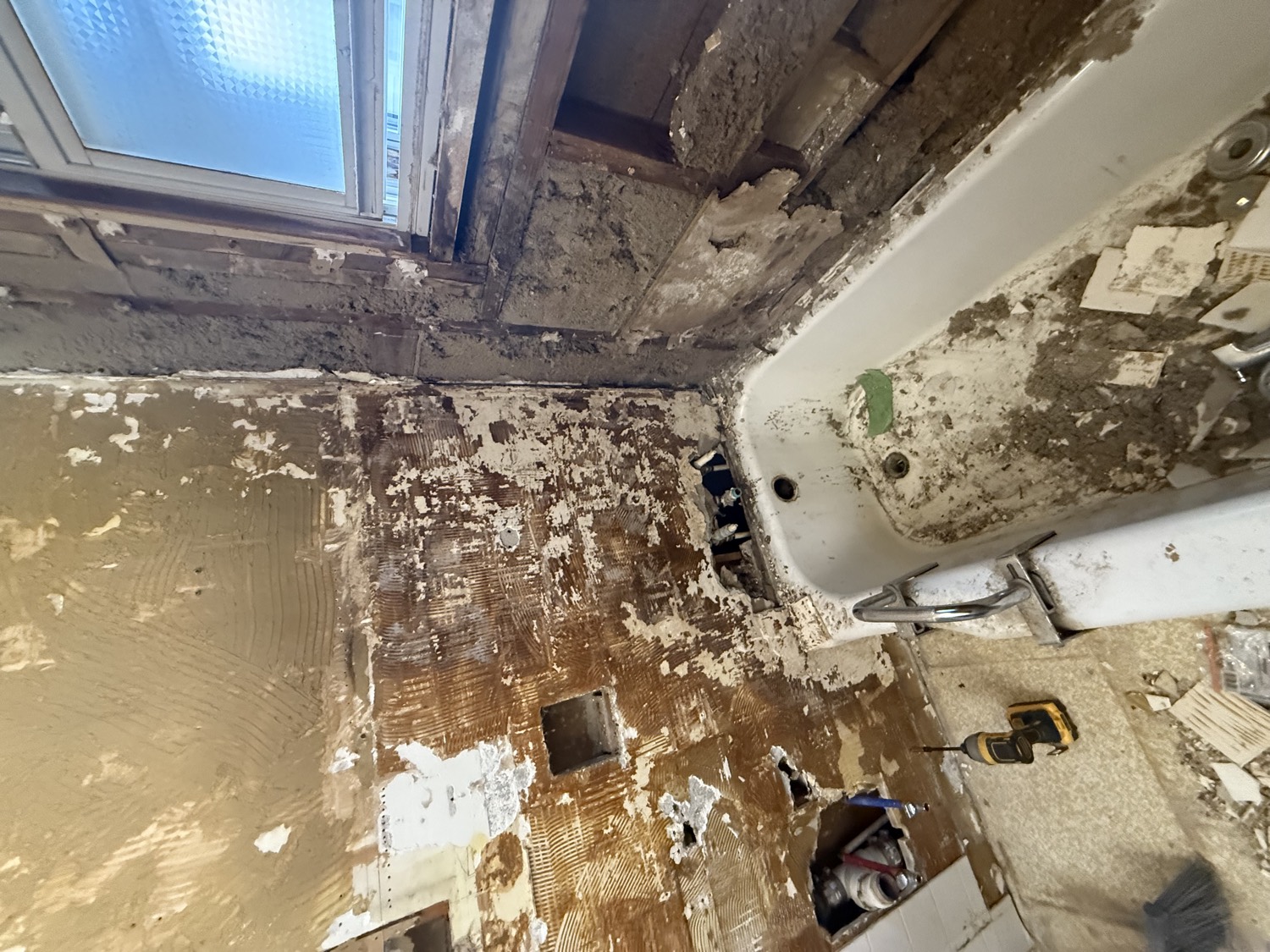 Bathroom stripped to the studs during demolition, old tub and window exposed