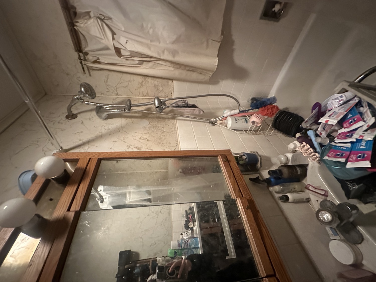 Old, cluttered bathroom with dated vanity and fixtures before remodeling