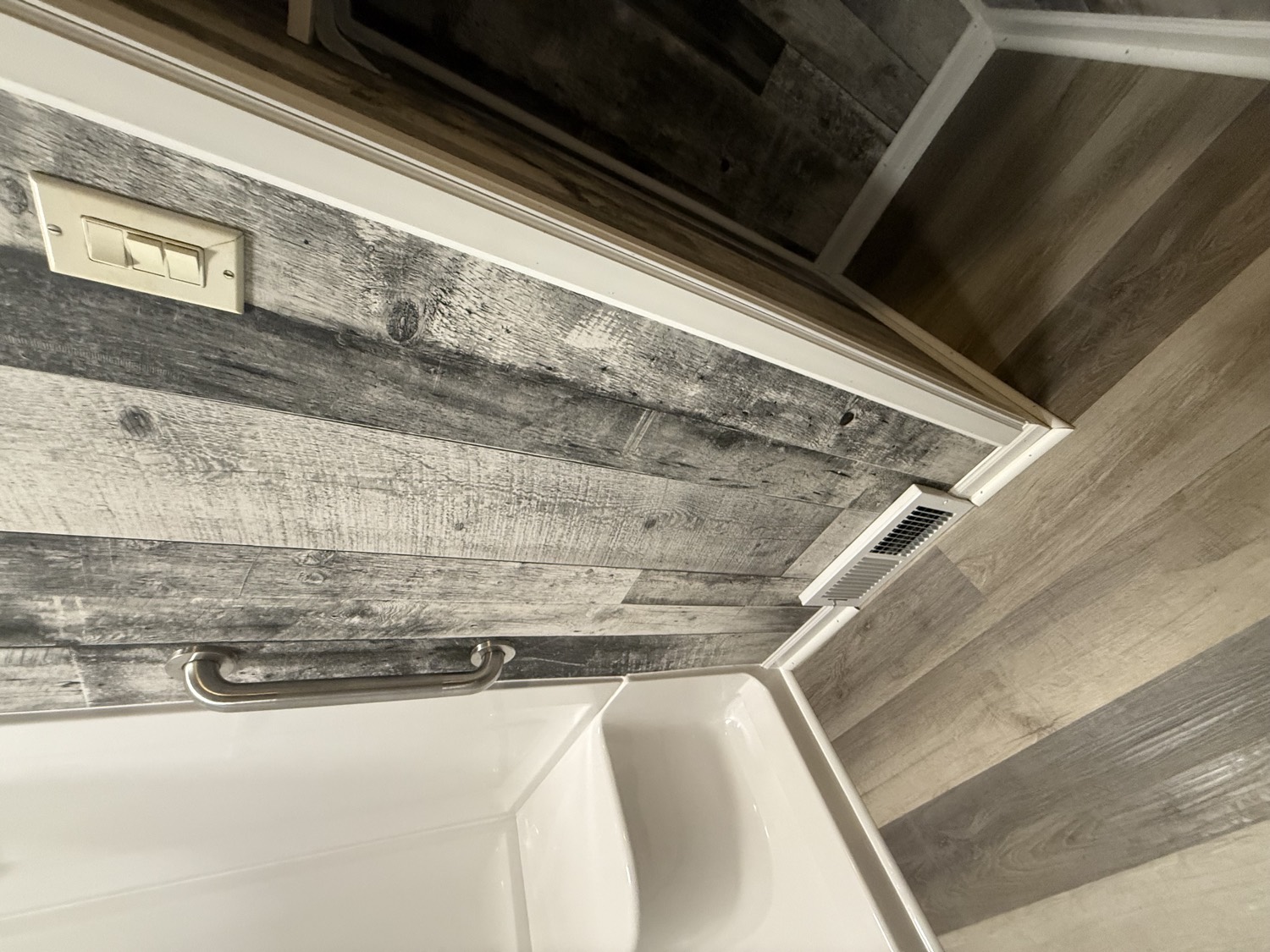 Walk-in shower with grab bar and rustic plank accent wall
