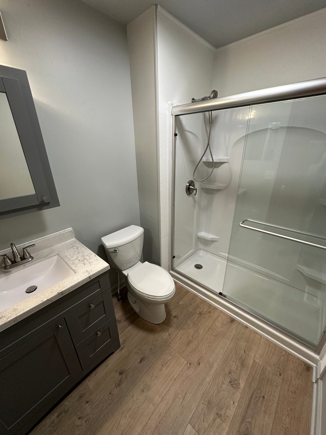 Finished St. Marys bathroom with a gray shaker vanity, framed mirror, and walk-in shower
