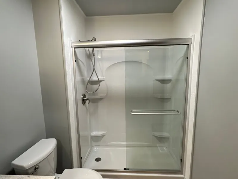 After: the low-step shower with sliding doors and a grab bar.
