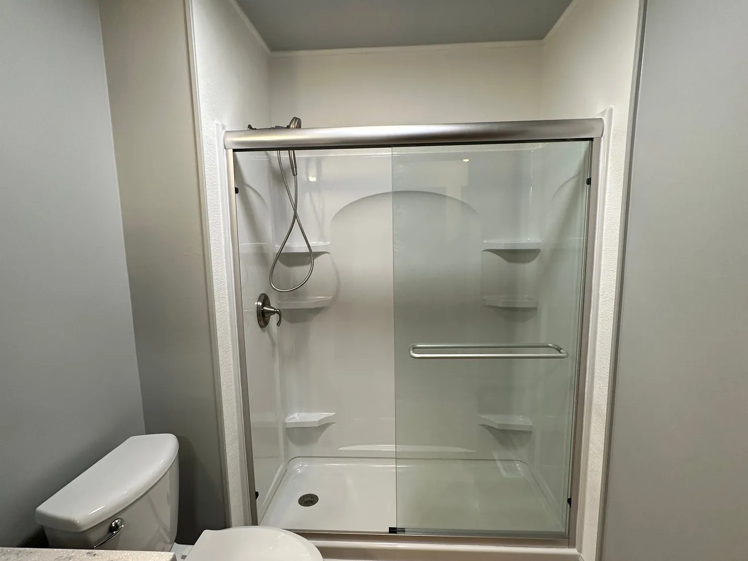 Tub replaced with a low-step walk-in shower, grab bar, sliding glass doors, and wood-look plank flooring