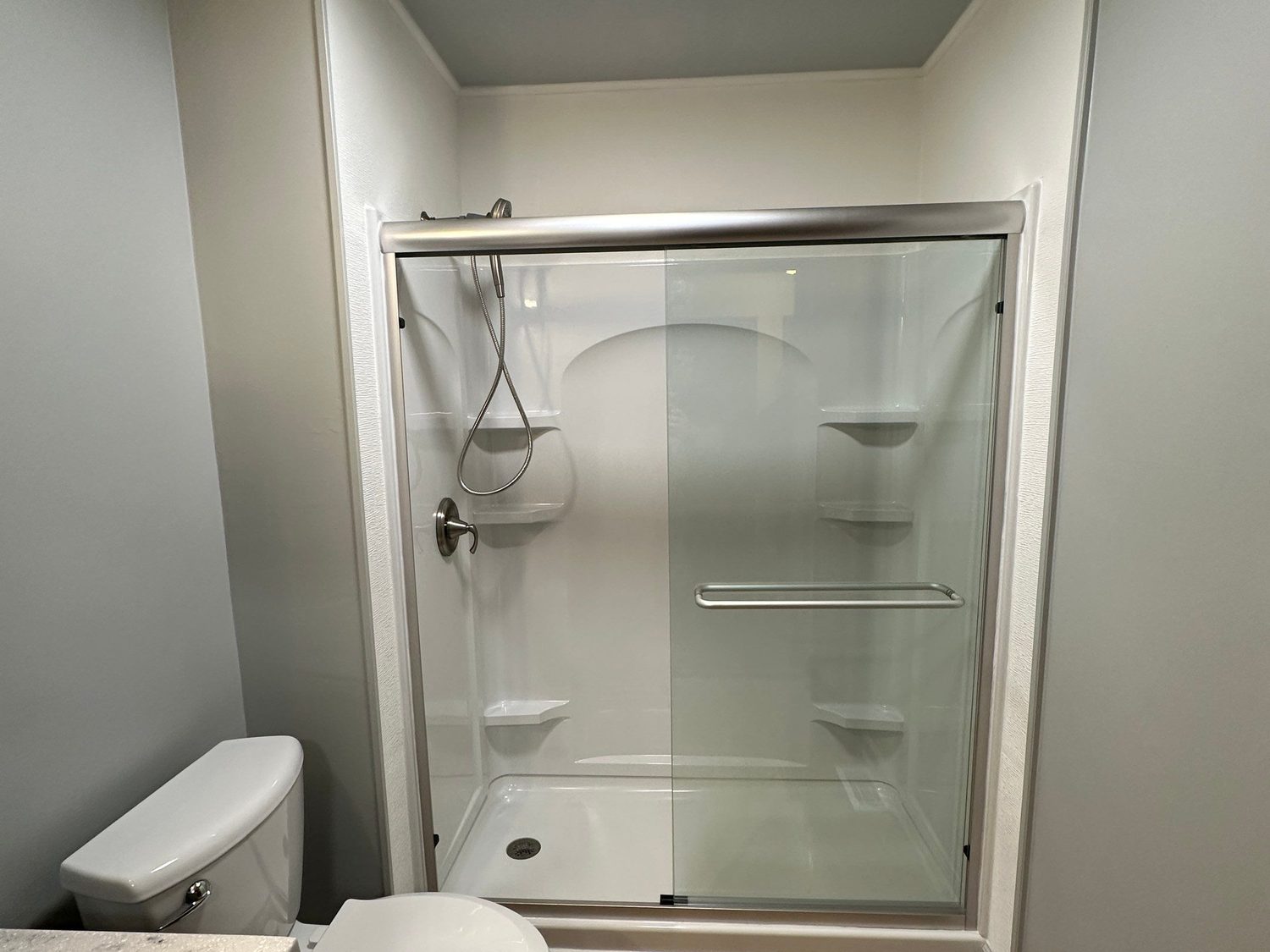 Tub replaced with a low-step walk-in shower, grab bar, sliding glass doors, and wood-look plank flooring