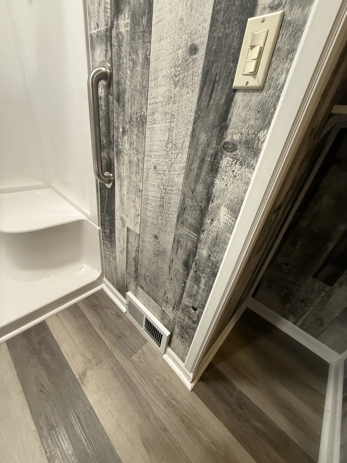 Walk-in shower with grab bar and rustic plank accent wall