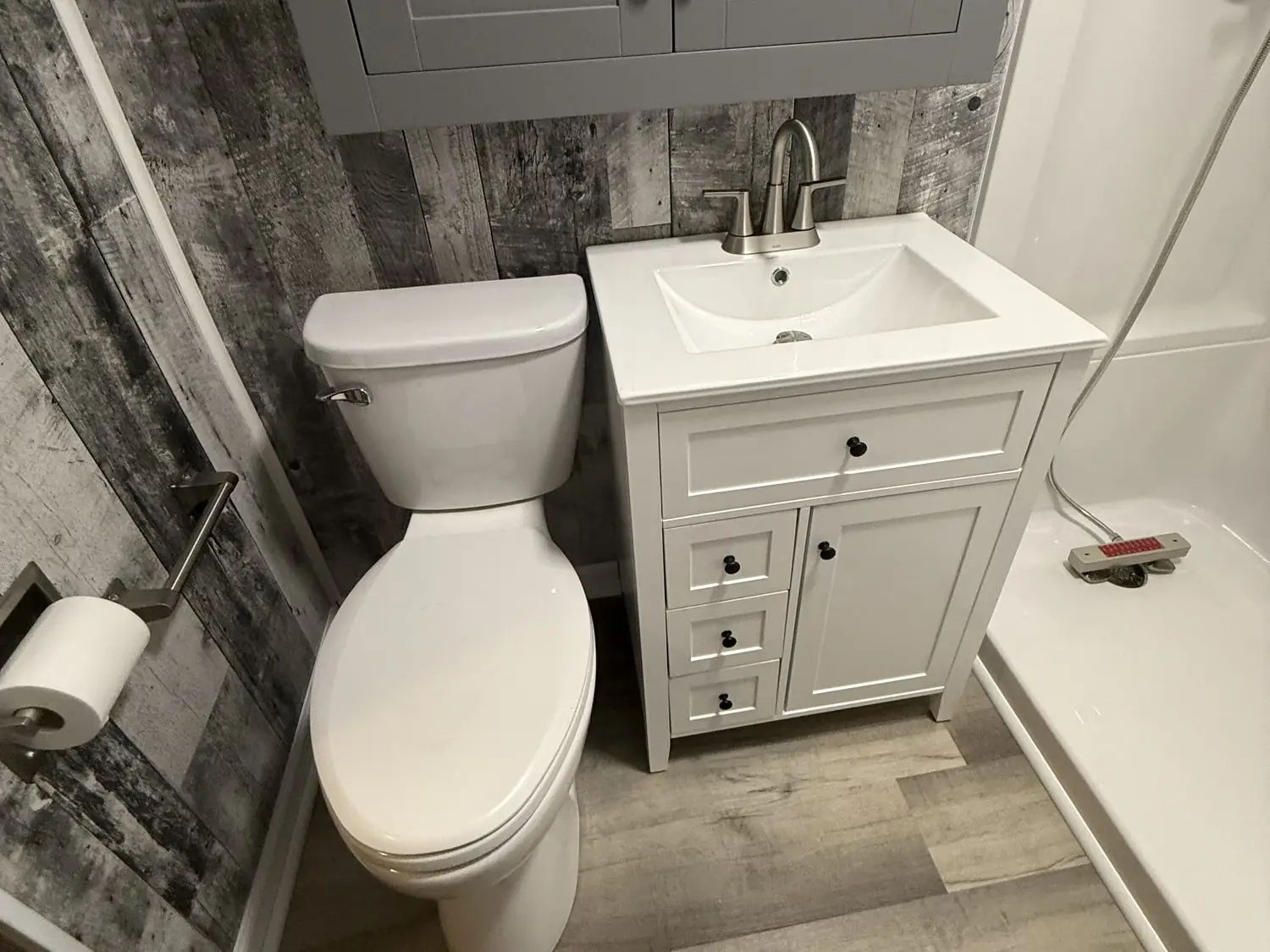 Updated bathroom with a new white vanity, comfort-height toilet, and rustic gray plank accent wall